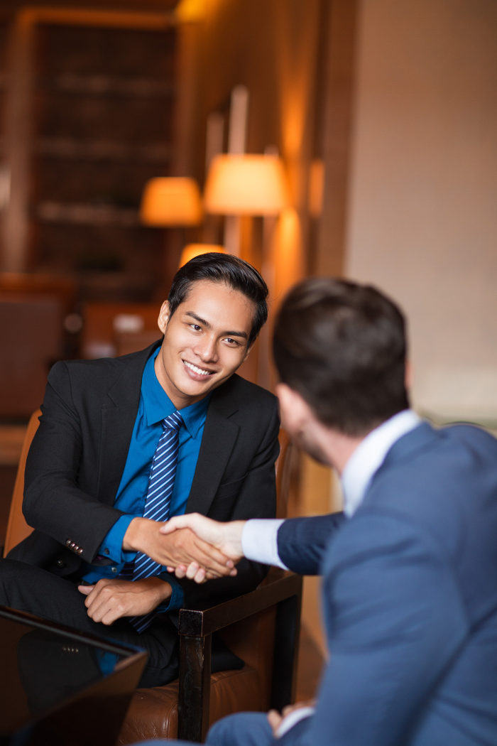 Two smiling partners shaking hands in a cafe