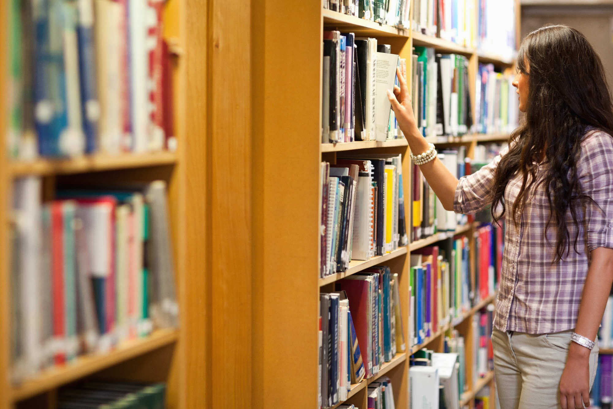 Young woman choosing a book in a library